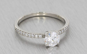 圆形明亮式diamo的nd ring housed in a 4 claw setting with grain set diamond shoulders