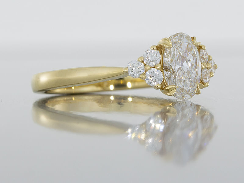 durham rose Yellow gold engagement ring featuring an oval centre diamond accented with small round diamonds main side