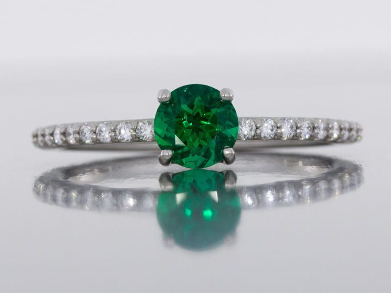 durham rose dainty platinum ring set with a round emerald and diamond shoulders front